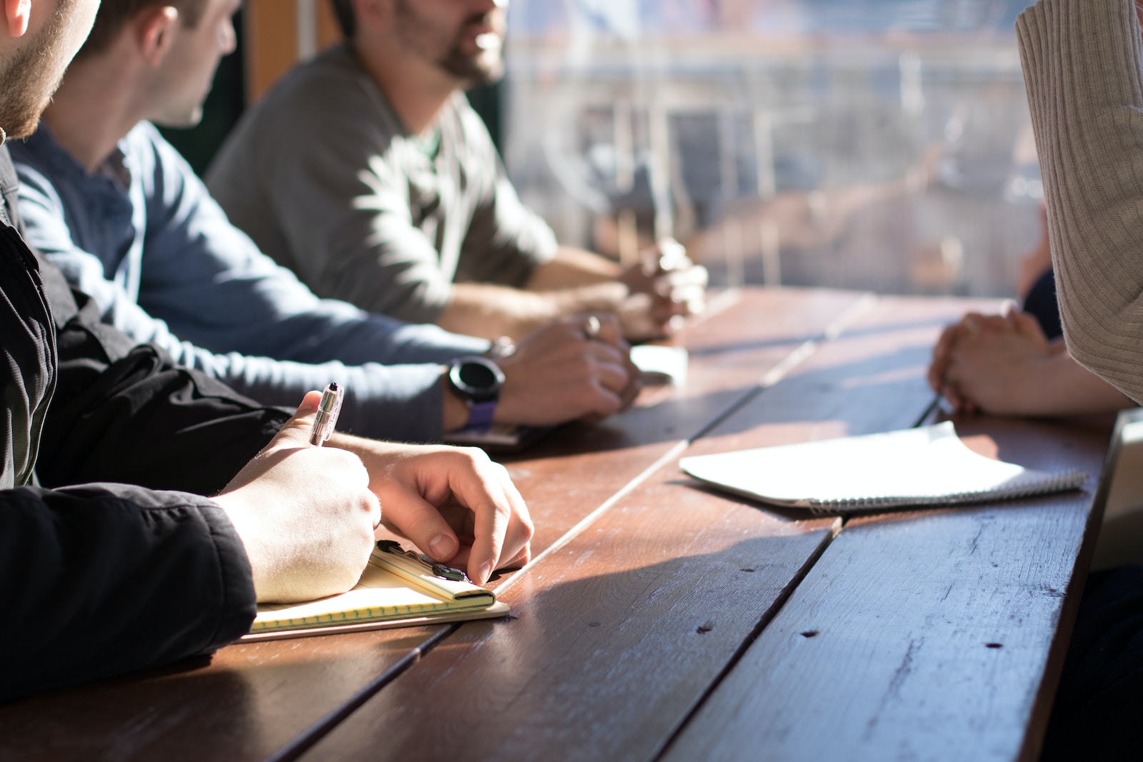 people sitting on chair in front of table while holding pens during daytime, business insurance