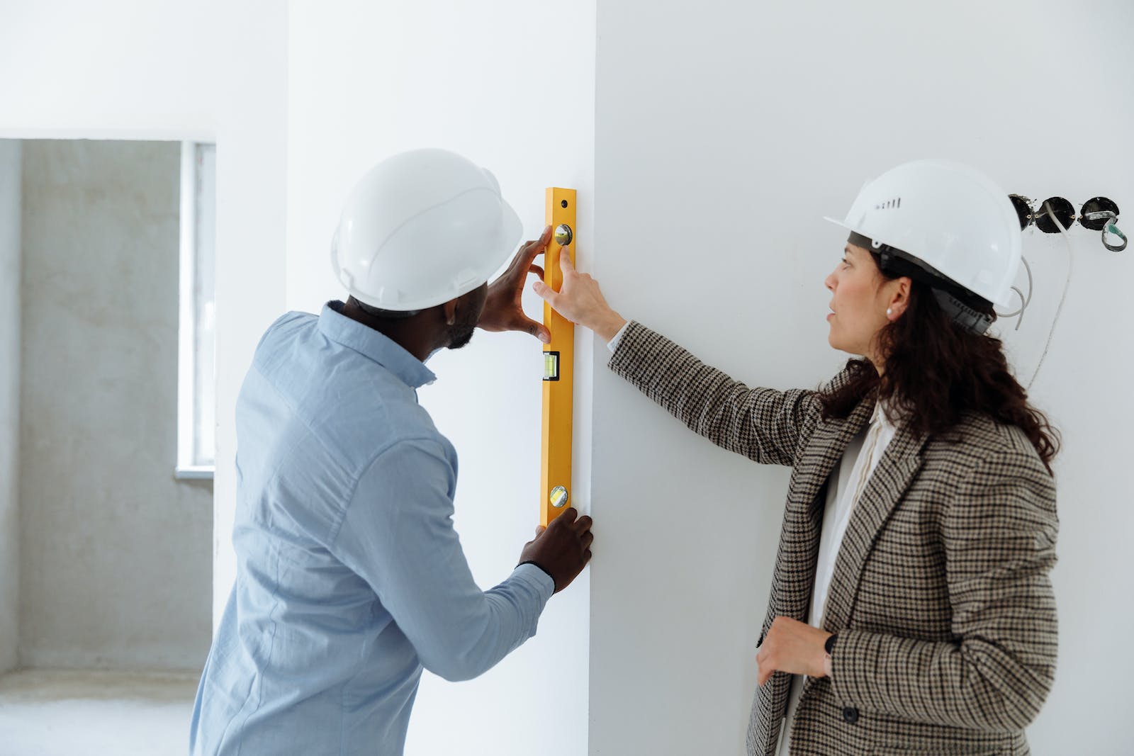 Woman and Man Holding a Level Bar on a Wall